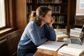 Jeune femme pensif assise à son bureau dans une pièce d'étude